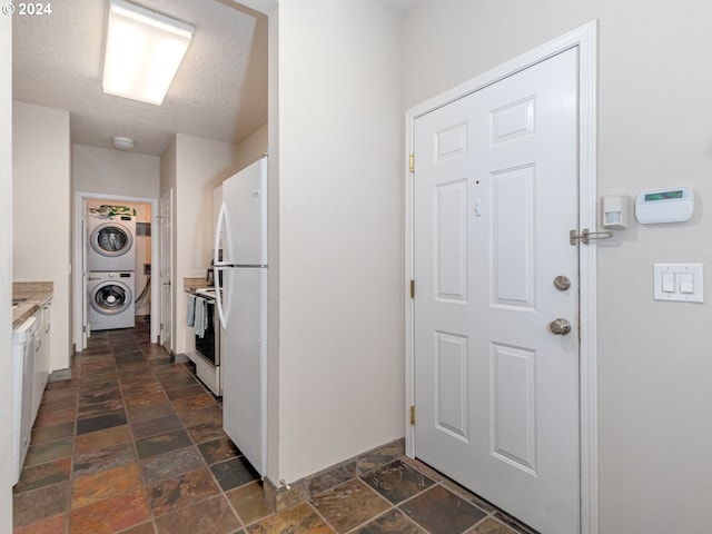 interior space featuring a textured ceiling and stacked washer / dryer