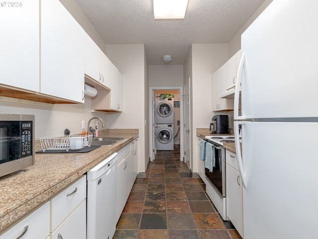 kitchen with a textured ceiling, white appliances, sink, white cabinets, and stacked washer and dryer