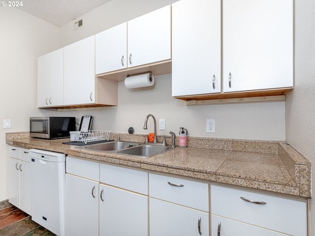 kitchen with white dishwasher, white cabinetry, and sink