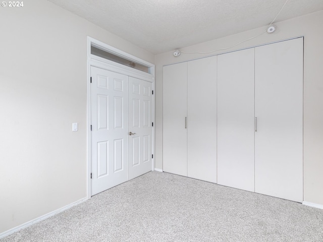 unfurnished bedroom featuring light carpet and a textured ceiling