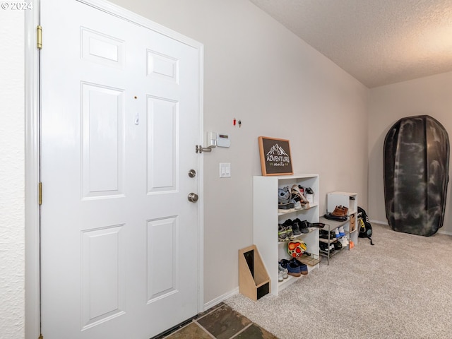 carpeted foyer entrance featuring a textured ceiling