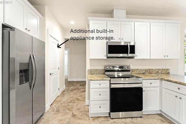 kitchen featuring stainless steel appliances, a barn door, white cabinets, and light stone counters