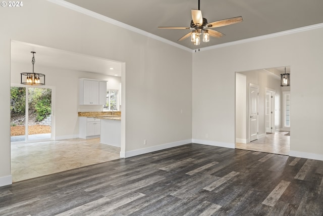 unfurnished living room with dark wood-type flooring, ornamental molding, and ceiling fan with notable chandelier