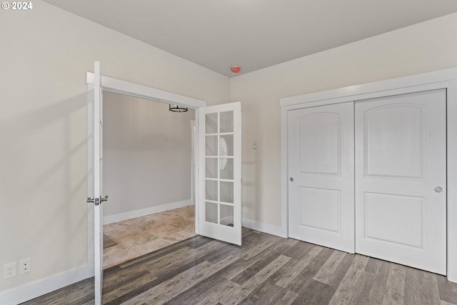 unfurnished bedroom featuring hardwood / wood-style flooring, a closet, and french doors