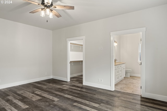 unfurnished bedroom with a spacious closet, dark wood-type flooring, a closet, and ensuite bathroom