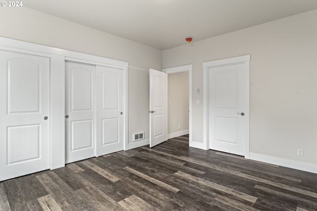 unfurnished bedroom with dark hardwood / wood-style flooring and a closet