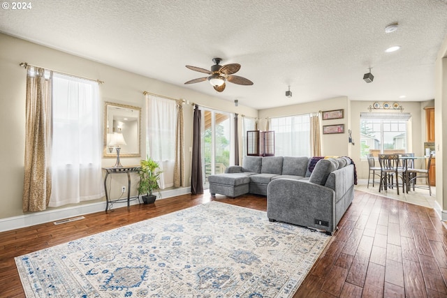 living room with a textured ceiling, wood-type flooring, and ceiling fan