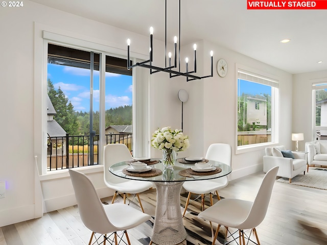 dining area with light wood-type flooring and a notable chandelier