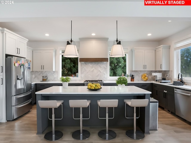 kitchen featuring a kitchen island, premium range hood, appliances with stainless steel finishes, and light hardwood / wood-style floors