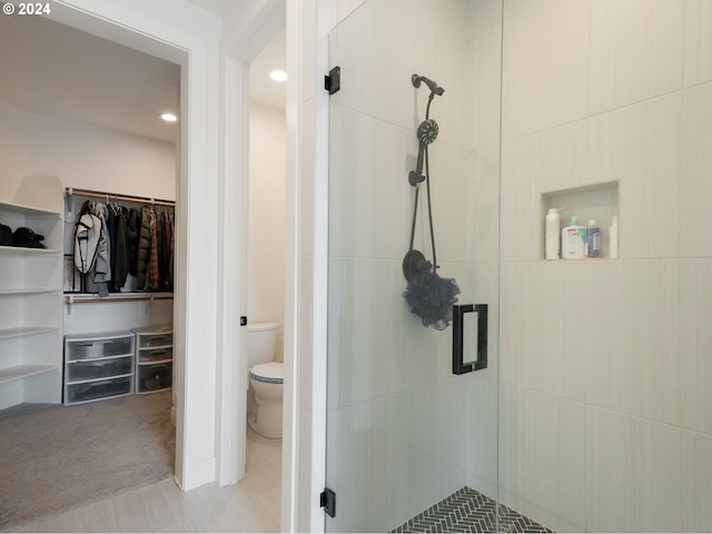 bathroom featuring toilet, tile patterned flooring, and a shower with door