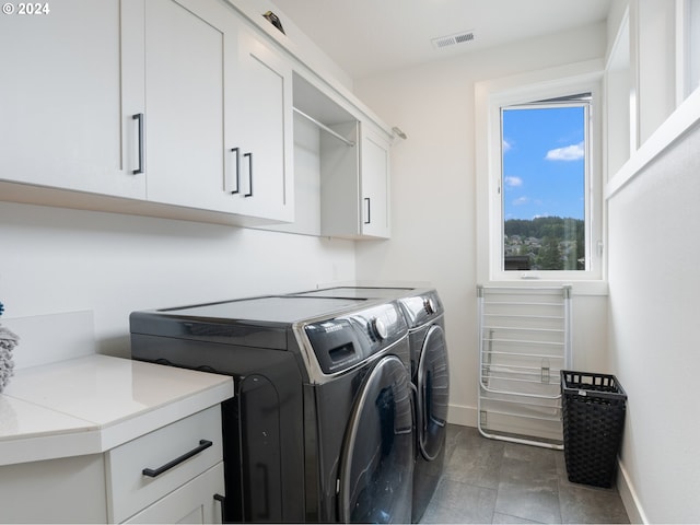 washroom featuring cabinets, washing machine and clothes dryer, and tile patterned flooring