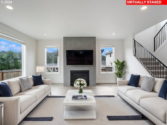 living room featuring a healthy amount of sunlight, light wood-type flooring, and a large fireplace