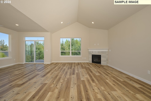 17374 SW Kalapuya Ln Unit 70, Sherwood, OR 97140 - unfurnished living room featuring light wood-style flooring, vaulted ceiling, baseboards, a tile fireplace, and recessed lighting