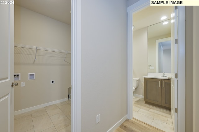 interior space featuring washer hookup, sink, hookup for an electric dryer, and light tile patterned floors