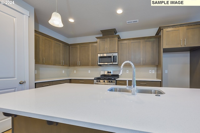 kitchen featuring stainless steel appliances, hanging light fixtures, sink, and backsplash