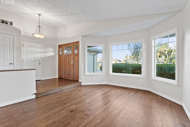 foyer entrance with vaulted ceiling, dark hardwood / wood-style floors, and a textured ceiling