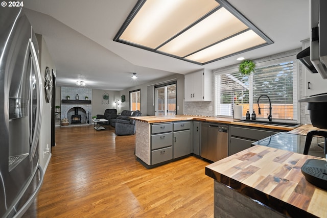 kitchen with stainless steel appliances, gray cabinets, butcher block countertops, and a fireplace