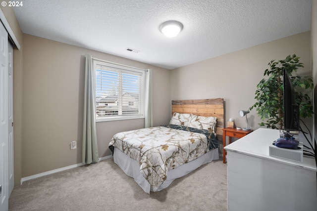 bedroom featuring a textured ceiling, light colored carpet, and a closet