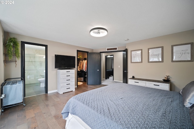 bedroom with a walk in closet, ensuite bathroom, a closet, and dark hardwood / wood-style floors