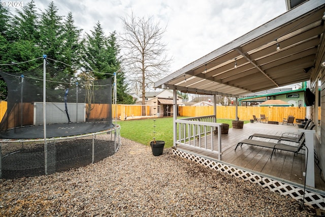 view of yard featuring a wooden deck and a trampoline