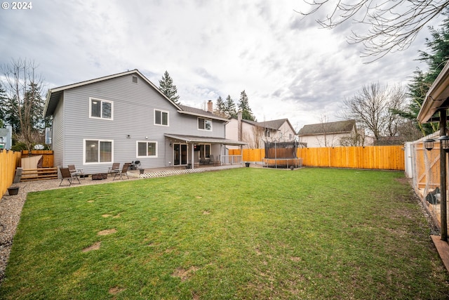 rear view of property with a patio area, a lawn, and a trampoline