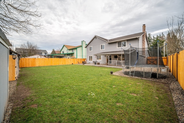 rear view of house featuring a yard and a trampoline