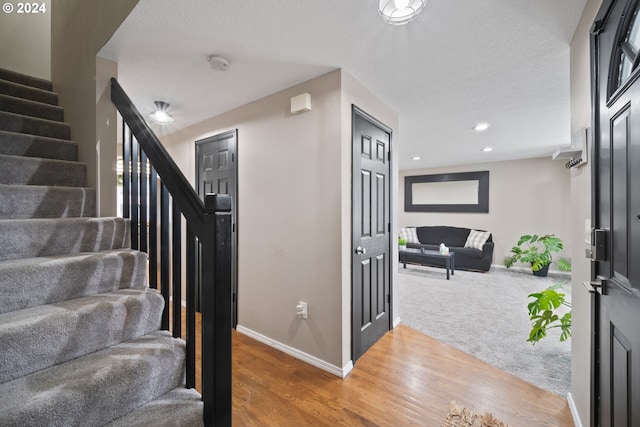 staircase with a textured ceiling and hardwood / wood-style floors