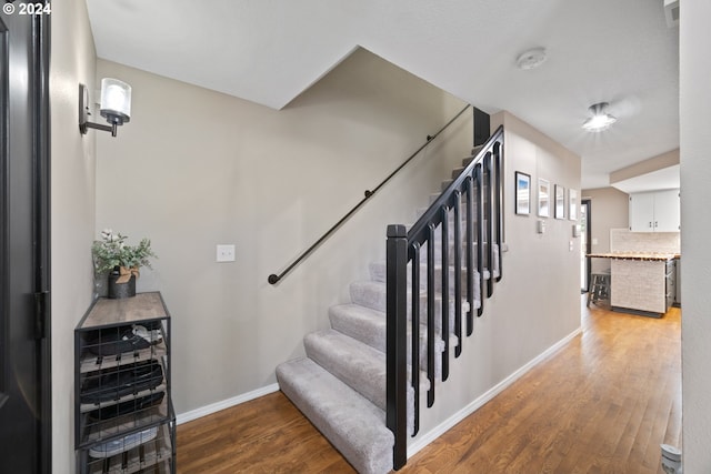 stairway with hardwood / wood-style floors and wine cooler