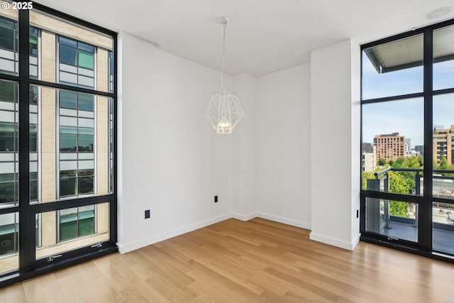 1025 NW Couch St Unit 716, Portland, OR 97209 - unfurnished room with expansive windows, a chandelier, plenty of natural light, and light wood finished floors