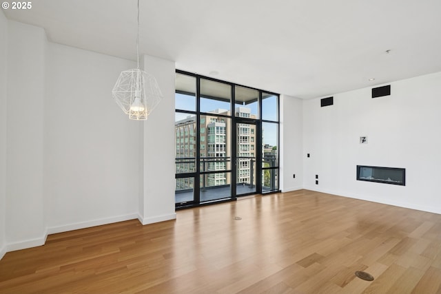 1025 NW Couch St Unit 716, Portland, OR 97209 - unfurnished living room featuring expansive windows, a chandelier, light wood-type flooring, a glass covered fireplace, and a view of city