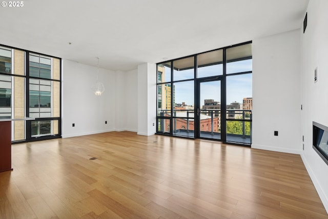 1025 NW Couch St Unit 716, Portland, OR 97209 - unfurnished living room with a wall of windows, wood finished floors, a glass covered fireplace, and a city view