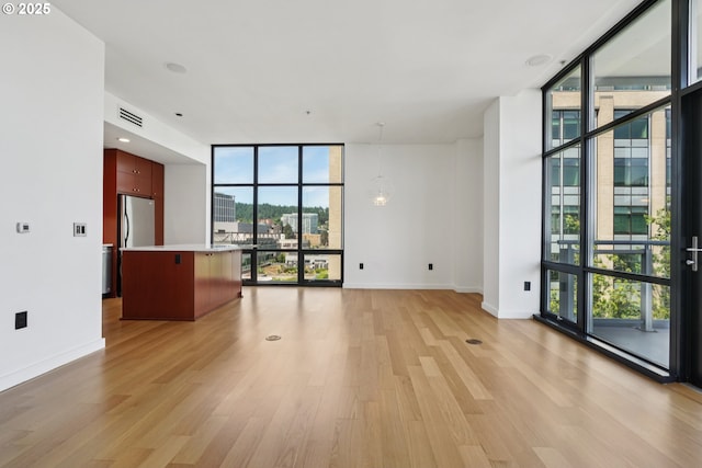 1025 NW Couch St Unit 716, Portland, OR 97209 - unfurnished living room featuring a wall of windows, healthy amount of natural light, light wood finished floors, and a chandelier