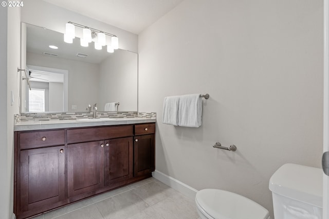 bathroom with tile patterned flooring, vanity, toilet, and backsplash