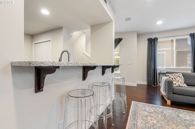 kitchen with sink, a breakfast bar area, and dark wood-type flooring