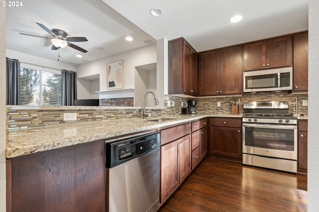 kitchen featuring light stone countertops, appliances with stainless steel finishes, tasteful backsplash, dark wood-type flooring, and sink