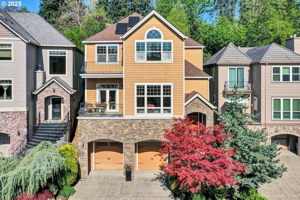 3649 Landis St, West Linn, OR 97068 - view of property with a balcony, concrete driveway, stone siding, a garage, and solar panels