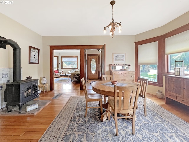 dining room with a wood stove, hardwood / wood-style floors, and a chandelier