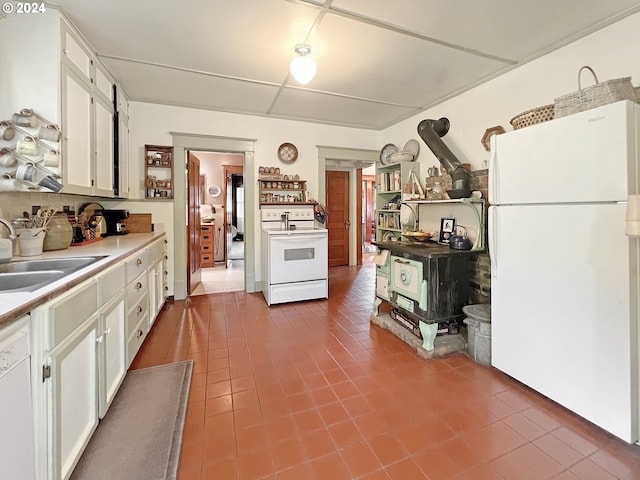 kitchen with dark tile patterned flooring, sink, white appliances, and white cabinetry