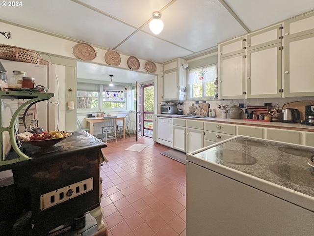 kitchen with range, decorative backsplash, white cabinets, sink, and dishwasher