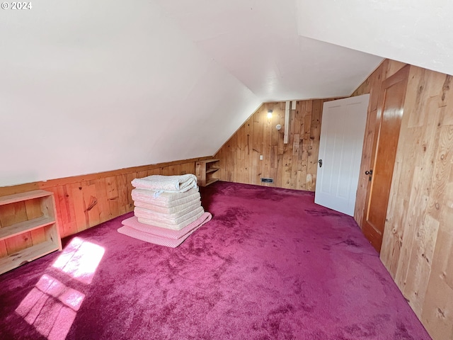 additional living space with wooden walls, vaulted ceiling, and carpet flooring