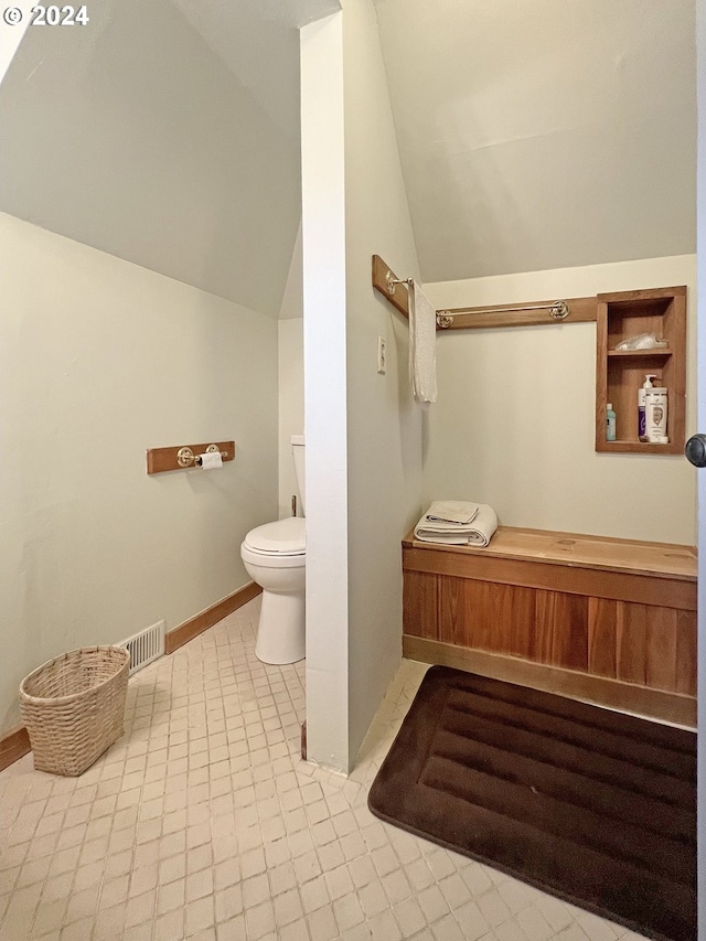 bathroom featuring tile patterned flooring, vaulted ceiling, and toilet