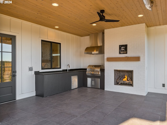 kitchen featuring ceiling fan, sink, wall chimney exhaust hood, and wooden ceiling