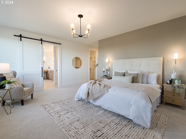 bedroom with an inviting chandelier, ensuite bathroom, a walk in closet, a barn door, and light colored carpet