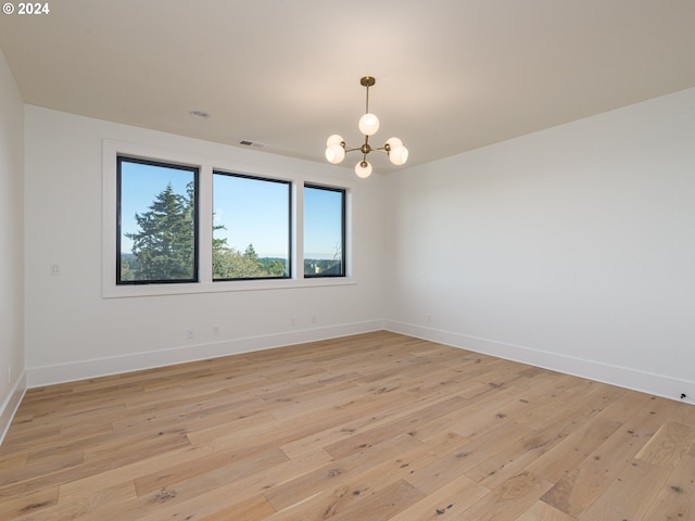 unfurnished room with an inviting chandelier and light wood-type flooring