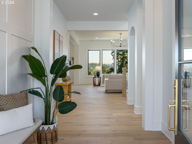 hallway with light wood-type flooring and an inviting chandelier