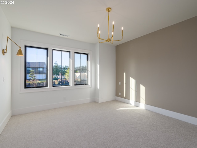 carpeted empty room featuring a chandelier