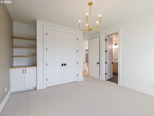 unfurnished bedroom featuring carpet flooring, ensuite bath, a closet, and an inviting chandelier