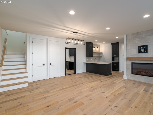 living room featuring sink, a large fireplace, and light hardwood / wood-style flooring