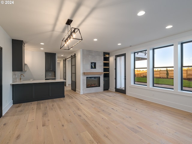 unfurnished living room with a fireplace, light wood-type flooring, and sink