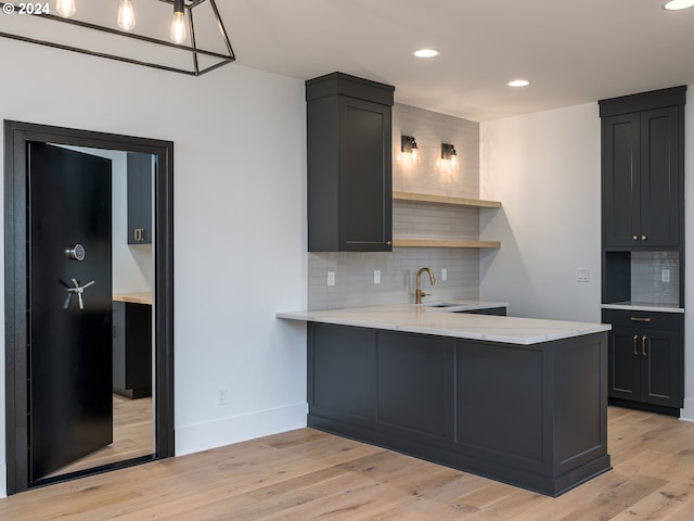 kitchen with tasteful backsplash, kitchen peninsula, and light hardwood / wood-style floors